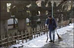 A worker walks away after shoveling snow off a court yard Sunday at a temple in Tokyo.