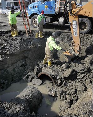 City employees fix a water-main break on Broadway between South Hawley and Stebbins streets in South Toledo. It was the city’s second major water-main break in a week, and a city official said he had no idea when Broadway — which sustained extensive buckling and heaving — might reopen.