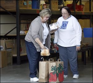 Amy Aschemeier, left, puts food items into a bag for Sue Fields at the Perrysburg Christians United food pantry.