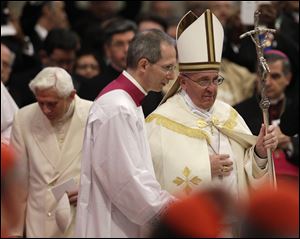 Pope Francis holds his pastoral staff after greeting Pope Emeritus Benedict XVI, left, ahead of a consistory Saturday inside the St. Peter's Basilica at the Vatican.