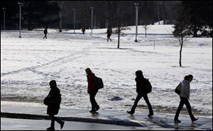 A fresh layer of snow covers the grass as students walk across campus near the Student Union at the University of Toledo today.