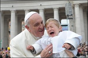 19-month-old Daniele De Sanctis, dressed up as a pope, is handed to Pope Francis as he is driven through the crowd during his weekly general audience Wednesday in St. Peter's Square at the Vatican.