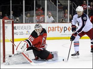 New Jersey Devils goaltender Cory Schneider, left, makes a save as Columbus Blue Jackets' R.J. Umberger looks for a rebound during the first period.