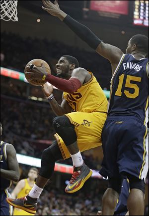 Cleveland Cavaliers' Kyrie Irving, left, jumps to the basket against Utah Jazz's Derrick Favors on Friday in Cleveland.