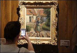 A visitor to the Fred Jones Jr. Museum of Art at the University of Oklahoma in Norman, Okla., takes a photograph of a piece called “Shepherdess Bringing in Sheep” by French impressionist artist Camille Pissarro at the museum.