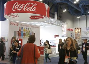 Attendees at a conference for dietitians pass by a booth sponsored by Coca Cola in Houston. As Americans struggle to improve their eating habits, big food companies are educating the professionals who help guide people on what’s healthy and what’s not.