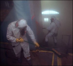 Workers removing lead paint.