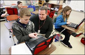 Sixth-grade teacher Jason Eaton helps Gabe Jan, 11, use his new Chromebook.