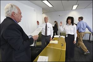 Ron Rothenbuhler, left, chairman of the Lucas County Board of Elections, swears in Dan DeAngelis as deputy director of the board and Gina Kaczala as the new director as outgoing director Meghan Gallagher and board member Jon Stainbrook leave the room.