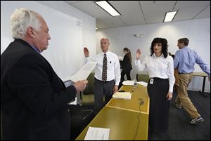  Lucas County Board of Elections chairman Ron Rothenbuhler, left, swears in Dan DeAngleis as deputy director of the board, and Gina Kaczala as the new director, during a board of elections reorganization meeting at One Government Cente today. Exiting the room are outgoing director Meghan Gallagher and board member Jon Stainbrook.
