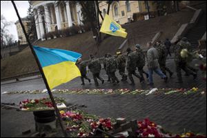 Ukrainian men wearing camouflage uniforms march along a street at a memorial for people killed during clashes with police at Kiev's Independence Square, Ukraine, today.