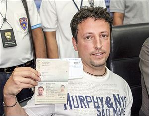 Luigi Maraldi of Italy shows his current passport at Phuket police station in Thailand. His old passport was used by a passenger aboard the missing airliner.