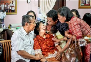 Family members comfort Chrisman Siregar, left, and his wife Herlina Panjaitan, the parents of Firman Siregar, one of the Indonesian citizens registered on the manifest to have boarded the Malaysia Airlines jetliner flight MH370 that went missing.