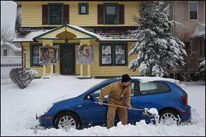 Peter Beck of West Toledo digs his car out of the snow on the street in front of his neighbors’ house. Seven inches of snow was recorded at Toledo Express Airport.