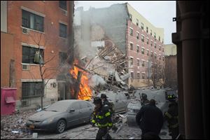 Firefighters work the scene of an explosion and building collapse in the East Harlem. The explosion leveled an apartment building, and sent flames and billowing black smoke above the skyline.