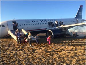 Passengers evacuate US Airways Flight 1702 after the pilot was forced to abort takeoff shortly after 6 p.m., after a tire on the plane's front landing gear blew out, Thursday in Philadelphia.