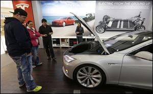Robert and Sarah Reynolds, left, check out a new Tesla all electric car with Tesla representatives John Van Cleave and Raven Rivera, right, Monday, March 17, 2014, at a Tesla showroom inside the Kenwood Towne Centre in Cincinnati. 