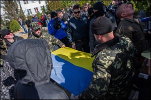 Ukrainian soldiers fold the Ukrainian flag, which was removed by a Crimean pro- Russian self-defense force at the Ukrainian Navy headquarters in Sevastopol, Crimea, today.