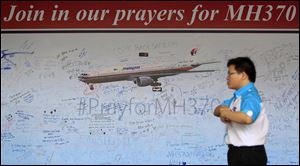 A man walks past a message board for passengers aboard a missing Malaysia Airlines plane, at a shopping mall in Petaling Jaya, near Kuala Lumpur, Malaysia, today.
