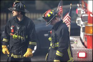 A firefighter, right, lowers his head at the scene of the fire that claimed two firefighters.