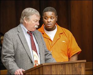 Tyrone Hoskins, 23, right, with public defender James MacHarg, was in Toledo Municipal Court Thursday. He faces murder, gang, bribery and drug charges.  