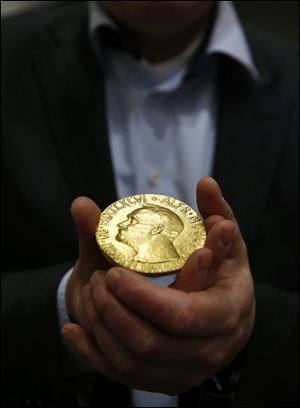 Bidder Ole Bjorn Fausa, of Norway, holds the 1936 Nobel Peace Prize medal today in Baltimore.