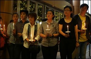 People hold candles during a ceremony in memory of passengers on board the missing Malaysia Airlines Flight MH370 in Kuala Lumpur, Malaysia Thursday.