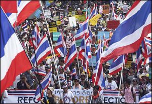 Thai anti-government protesters hold national flags and banners that read 'Reform before the election', fill the street during a mass rally today in Bangkok, Thailand.