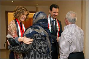 First lady Asma Assad, left background, and Syrian President Bashar Assad, right background, shaking hands with Syrian teachers in Damascus earlier this month.