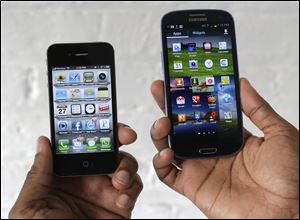 The Apple iPhone 4s, left, is displayed next to the Samsung Galaxy S III.