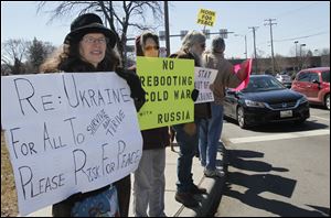 Janice Flahiff of Toledo, Karen Wolf of Bowling Green, and Jeff Zenz of Whitehouse protest in the Westgate area of Toledo. Coalition members urged the United States not to take military action against Russia.
