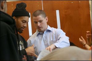 Navigation Project Director Brad Clark, center, talks with Toledo resident Marcus Ashford, left, as Ashford signs up to see a navigator about enrollment in the Affordable Care Act's health care exchange Monday at the downtown branch of the Toledo-Lucas County Library in Toledo.