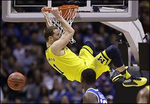 Michigan's Nik Stauskas dunks during the second half of an NCAA Midwest Regional final college basketball tournament game against Kentucky Sunday, March 30, 2014, in Indianapolis. 