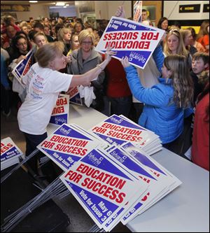 Ruthann Finch hands out levy yard signs after a pep rally at Northview High School in Sylvania in support of the district’s 3.8-mill continuing levy request on the May 6 ballot.