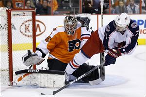 Columbus Blue Jackets' Nick Foligno, right, tries to get a shot past Philadelphia Flyers' Steve Mason during the first period.