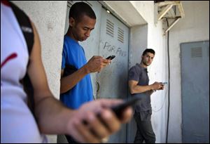 Students gather behind a business looking for a Internet signal for their smart phones in Havana, Cuba, Tuesday.