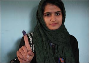 An Afghan young woman shows her inked finger after casting her vote at a polling station in Herat, Afghanistan, Saturday, April 5, 2014. Afghans flocked to polling stations nationwide on Saturday, defying a threat of violence by the Taliban to cast ballots in what promises to be the nation's first democratic transfer of power. (AP Photo/Hoshang Hashimi)