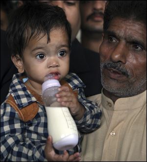 An unidentified family member with nine-month-old Mohammad Musa leave after the boy's court appearance today in Lahore, Pakistan.