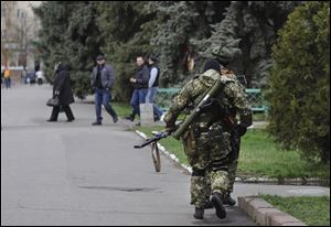 Armed pro-Russian activists walk through a street near to the seized Ukrainian regional administration building today in the eastern Ukrainian town of Slovyansk,  Ukraine.