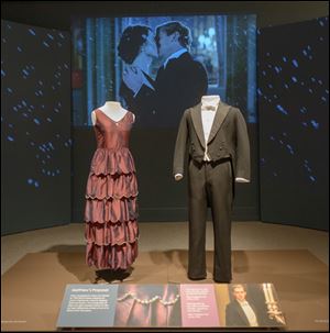 At the Winterthur Museum Costumes of Downton Abbey exhibition, fans of the British TV show can ogle such finery as the red dress and dapper suit worn by characters Mary and Matthew for their Season 2 engagement scene, shown on the screen in the background. 