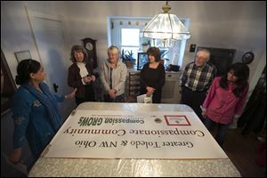 From left, Dr. Samina Hasan, Valerie Garforth, Kathleen Moorman, Nazife Amrou, Tom Mitchell, and Kim Thistlethwaite look over a sign at their planning meeting.