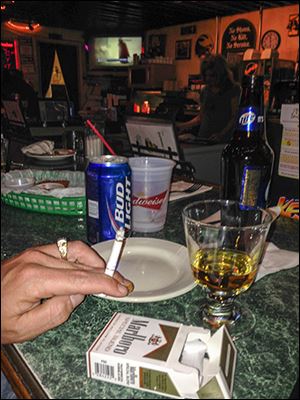 Patrons smoke at Delaney’s in Toledo despite Ohio’s law that bans smoking in public places. Enforcing the ordinance remains elusive for many state and county agencies since the law went into effect nearly eight years ago.