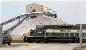 A diesel locomotive moves through the Prairie State Energy Campus facility in Belleville, Ill., with a domed storage unit in background. With annual rate increases of 5 percent planned through 2019 — costing homes and businesses 25 percent more five years from now — some people are questioning how much faith Bowling Green should maintain in a controversial coal-fired power complex in southern Illinois. 