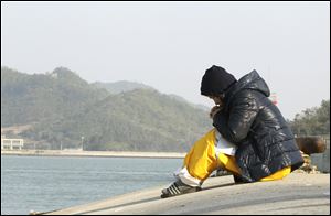 A relative of a passenger aboard the sunken ferry Sewol prays as she waits for her missing loved one today at a port in Jindo, South Korea.