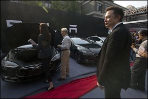Tesla Motors CEO Elon Musk, right, looks on as a set of Tesla Model S sedans are delivered to its first customers in China at an event today in Beijing.