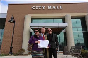 Debra Young, center, representing Safer Oak Park and Safer Hazel Park Coalition and campaign manager for Andrew Cissell, right, holds over 1,600 petitions, with Tim Beck, co-founder of the Safer Michigan coalition, at the Oak Park City Hall.