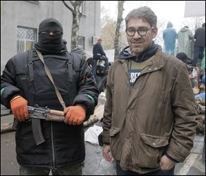 In this photo taken on Sunday, April 13, a reporter Simon Ostrovsky, right, stands next to a Pro-Russian gunman at a seized police station in the eastern Ukraine town of Slovyansk. Pro-Russian gunmen in eastern Ukraine say they are holding an American journalist captive. Ostrovsky, a journalist for Vice News, has not been seen since early Tuesday.