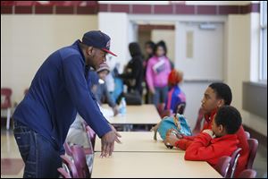 Wrestling coach Roshawn Jones, left, talks to brothers Ayden Braziel, 14, center, and Rayvon Braziel, 10, right, in Scott High School’s cafeteria about joining his central-city gym, Soul City Boxing and Wrestling.
