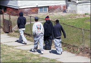 Twins Devon, center right, and Davon Lewis, back in the sweatshirt and sweatpants, walk with their friends. The brothers don’t go to Soul City Boxing as often as they have in the past.