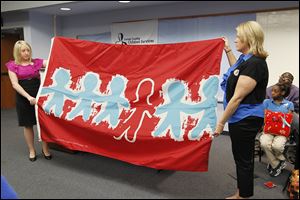 Christina DeSilvis, left, and Danielle Stroble, case workers with Lucas County Children Services, display the Child Abuse flag during a memorial to remember children in the county who suffered abuse and neglect between April, 2013, and April, 2014.